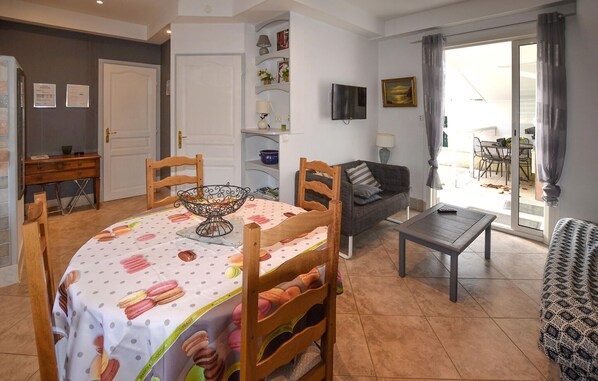 A dining area with a table set for four, a sofa, a TV, and a view of the outside. - 1 bedroom beautiful home in Vaison-la-Romaine (Vaison-la-Romaine)