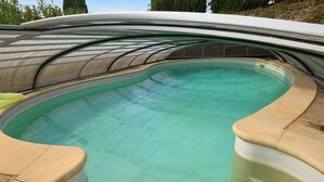En pool med en böjd kant och ett överbyggt område.