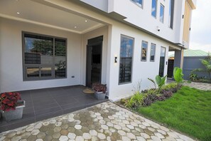 A modern two-story house with a covered patio area, large windows, and a well-maintained lawn. - Casa Maria facility, Spacious Home Sleeps 4–8, Perfect for Families & Groups (Kumasi)