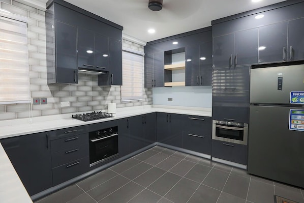 A modern kitchen with dark cabinetry, a stainless steel refrigerator, and a gas stove.