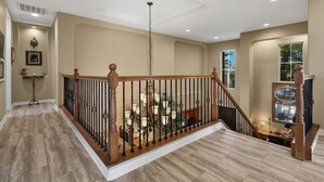 Ein geräumiger Innenraum mit einer Holztreppe, beigen Wänden und einer Kristallleuchter.