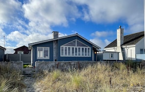 A single-story house with a gabled roof, a chimney, and a large window.