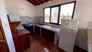 A compact kitchen with a wooden ceiling, a white refrigerator, a stove, and a sink. - La Isla Del Descanso (Puerto Villamil)