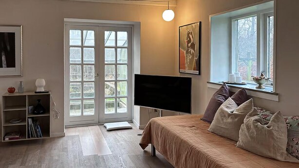Une chambre à coucher comprenant un lit, une télévision, une fenêtre et une porte donnant sur un balcon.