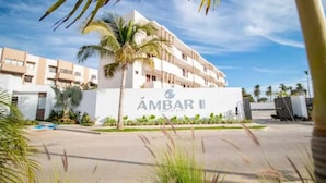 A modern building with a sign reading "ÁMBAR II" and a palm tree in the foreground. - Apartment in private condominium near the sea (Mazatlán)