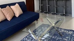 A modern living room with a blue sofa, a glass coffee table, and a ceiling fan. - Apartment in private condominium near the sea (Mazatlán)