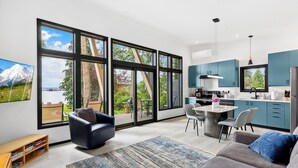 Una cocina moderna con ventanas amplias, un comedor y una sala de estar con sofá y alfombra.