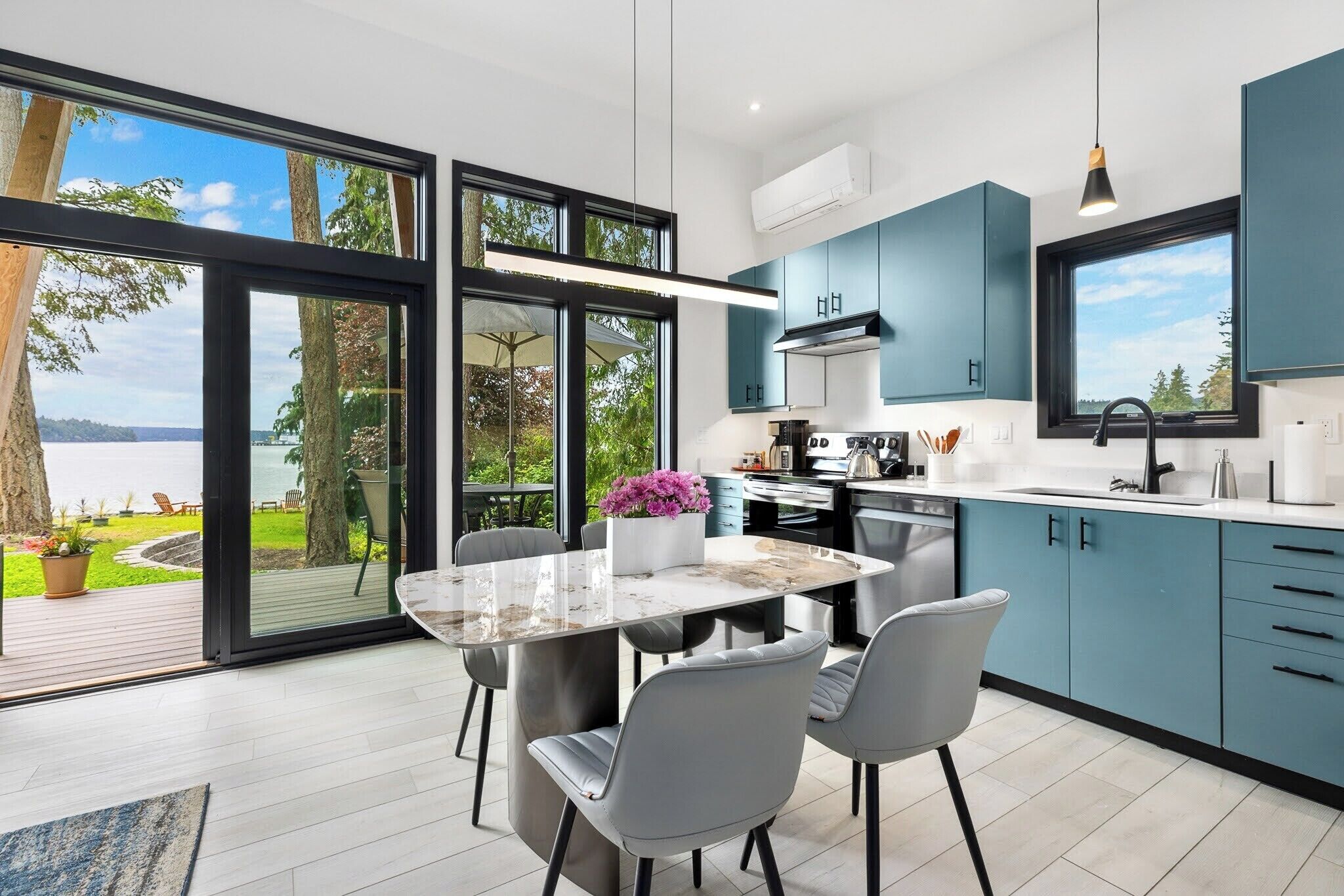 Una cocina moderna con una isla grande, armarios azules y vistas al exterior.