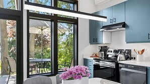 Una cocina moderna con armarios azules, una encimera de mármol blanco y una ventana con vistas a una terraza.