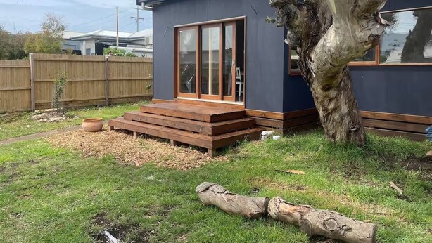 Een modern huis met een grote boom in de tuin.