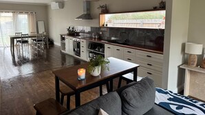 Een moderne keuken met witte kasten, een donker aanrecht en een raam met uitzicht op een tuin.