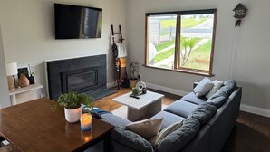 Een woonkamer met een open haard, een groot raam, een bank en een televisie.
