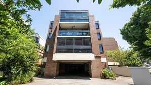 Un edificio a più piani con tetto piatto, ampie finestre e ingresso coperto.