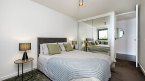 Una camera da letto moderna con un letto grande, due comodini, uno specchio e vista esterna.