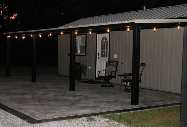 A covered patio area with a seating arrangement and string lights. - Charming tiny house in Russellville (Russellville)