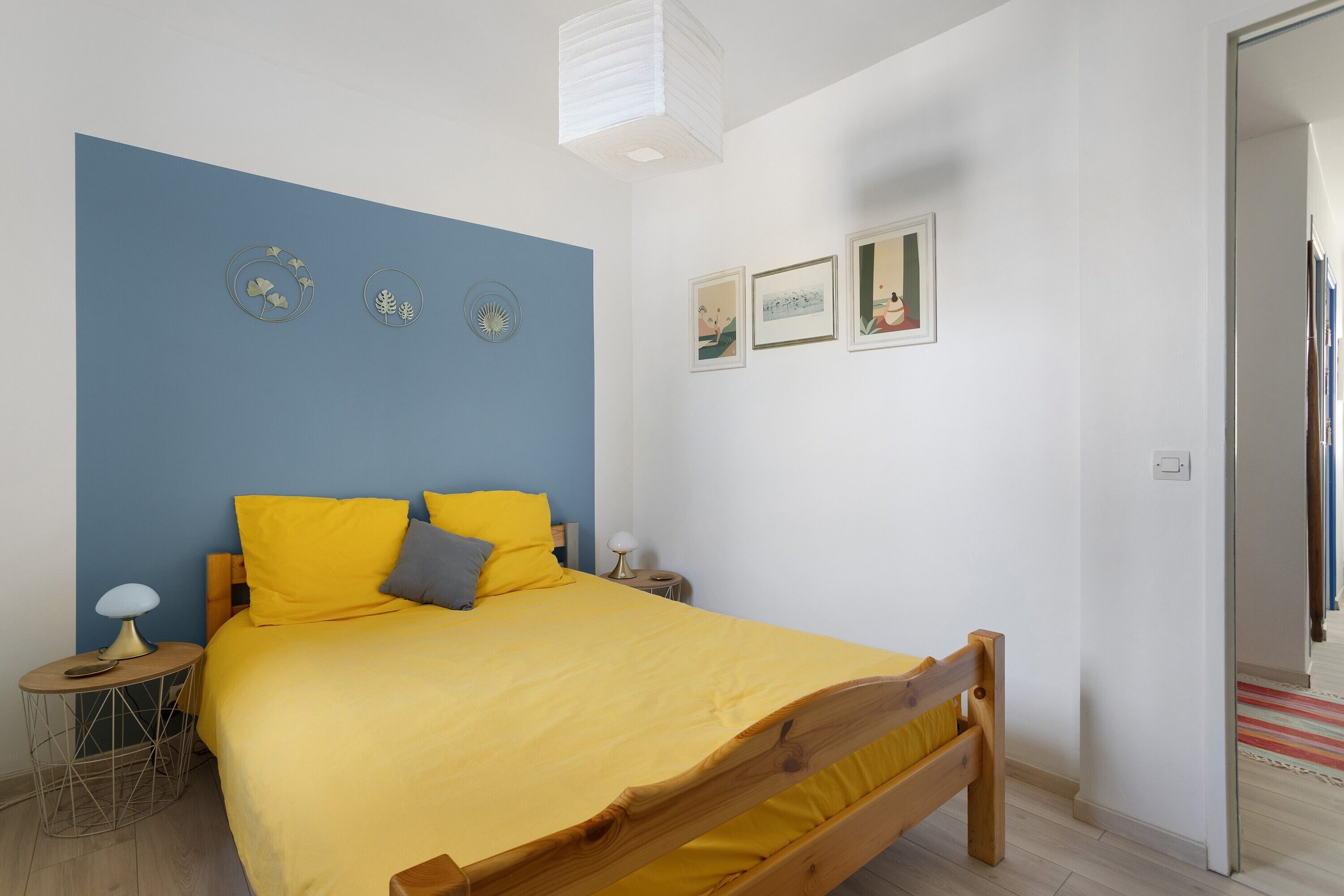 Un dormitorio con cama, mesita de noche, lámpara y decoración en la pared.