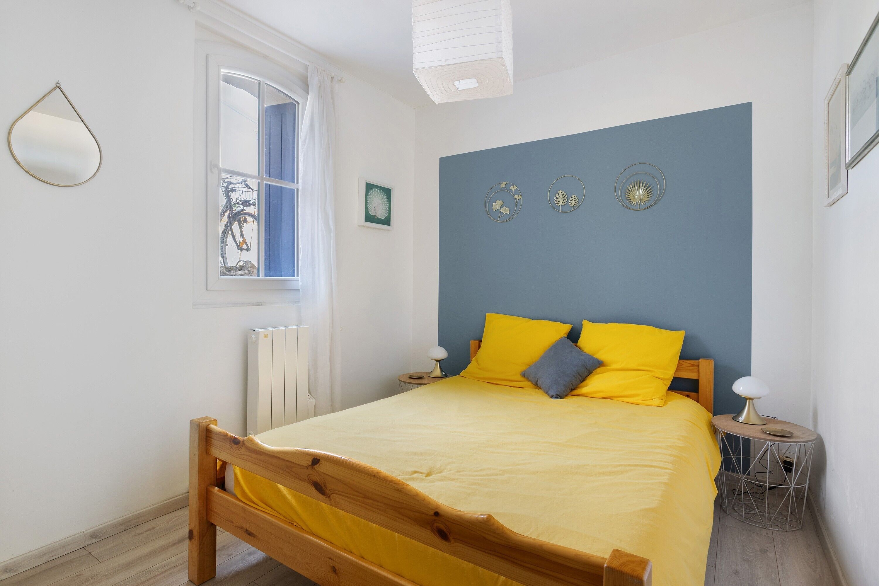 Un dormitorio con cama, ventana, radiador y adornos en la pared.