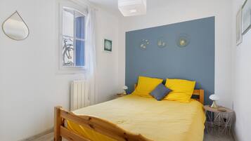 Un dormitorio con cama, ventana, radiador y adornos en la pared.