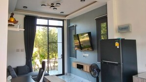 A modern kitchen with a built-in refrigerator, a flat-screen TV mounted on the wall, and a dining area with a table and chairs.