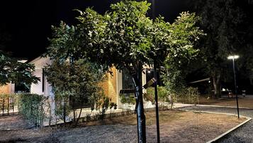 A well-lit outdoor area with a tree, a stone wall, and a lamp post.