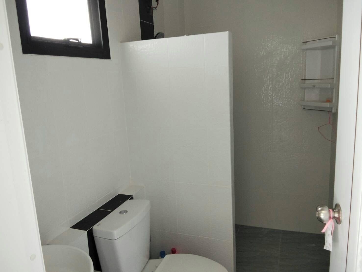 A small, compact bathroom with a toilet, a shower stall, and a white sink.