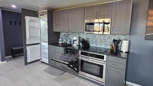 A modern kitchen with grey cabinets, stainless steel appliances, and a tiled backsplash.