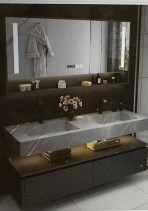 Ein Badezimmer-Waschtisch mit großem Spiegel, Marmorplatte und dunklem Holunterschrank.