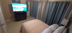 A bedroom with a bed, a television on a dresser, and curtains. - Golden Haven –Comfort in the Heart of Paradise in The Bahamas - entire apartment (Nassau)