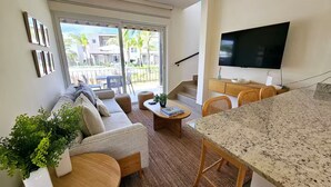 A modern living room with a sofa, coffee table, and a TV mounted on the wall.