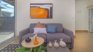 Un soggiorno moderno con un divano grigio, un tavolino rotondo e un quadro appeso sopra.