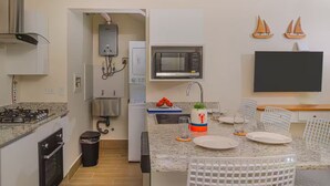 Una cucina compatta con piano cottura a gas, forno a microonde e lavandino piccolo. Due decorazioni a tema vela adornano la parete.