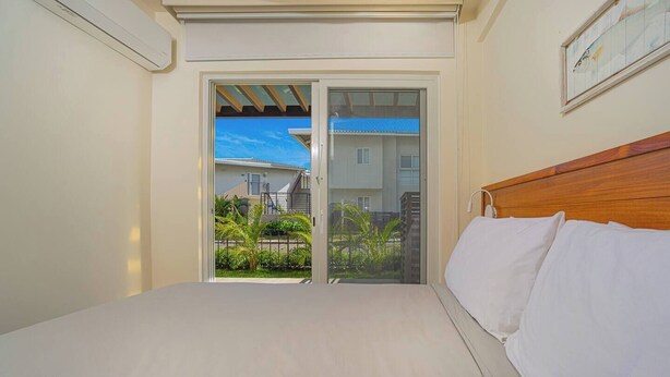 Una camera da letto con un letto, una testata in legno e vista su un edificio tramite una porta in vetro.