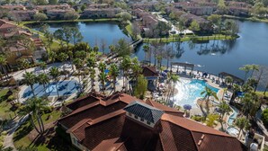 Zona residencial con piscina, cancha de tenis y un puente sobre un lago.