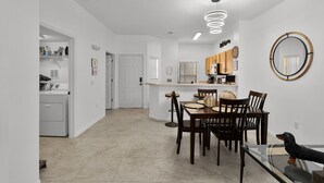 Una cocina moderna con una isla central, una zona de comedor con sillas de madera y una mesa de vidrio.