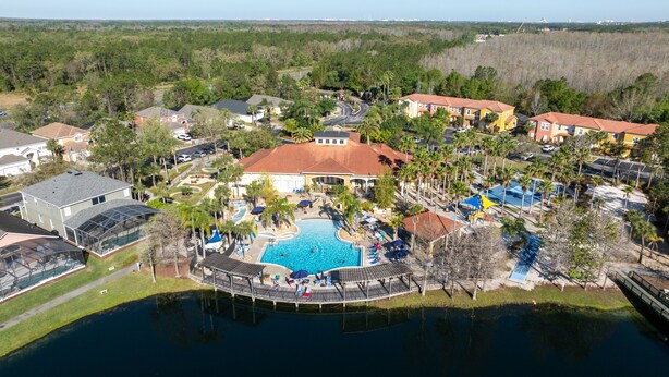 Vista aérea de una zona residencial con una gran piscina rodeada de palmeras y viviendas.