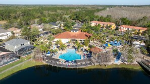 An aerial view of a residential area with a large swimming pool surrounded by palm trees and houses. - 3BR/3BA Townhome with Resort Pool, Clubhouse & Lake – Minutes from Disney (Kissimmee)