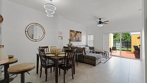 Un salón amplio con una mesa de comedor, sillas, un sofá y un ventilador de techo.