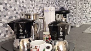 Una cocina con dos cafeteras italianas, una máquina de café y una taza sobre un tapete.