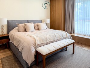 A neatly arranged bedroom with a bed, bedside tables, a bench, and a window with curtains. - Luxury by the sea Unmatched Comfort (Bucerías)