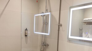 A modern bathroom with a glass-enclosed shower, a vanity with a mirror, and a toilet.
