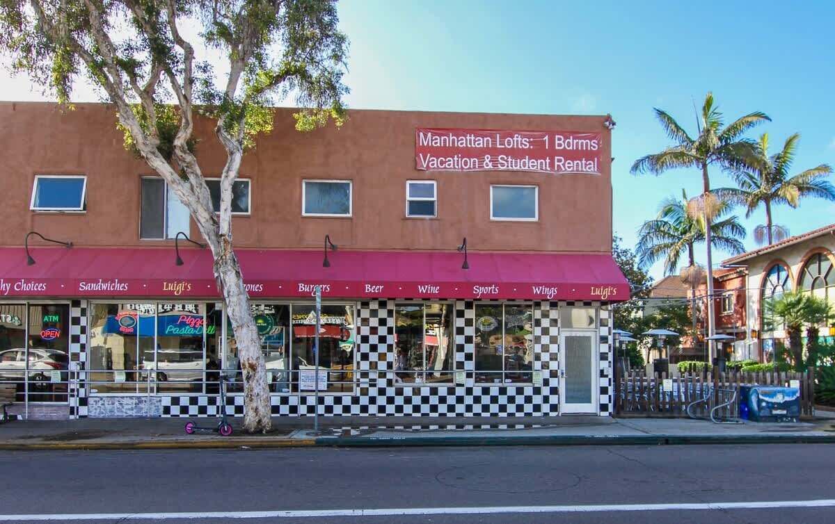 A building with a red awning advertising Manhattan Lofts for vacation and student rental.