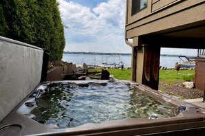 A hot tub in a backyard with a view of a lake and a building in the background. - Unplug in Style at This Premier Minnesota Lakefront Haven (Buffalo)