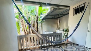 Un escalier orné de carreaux décoratifs menant à un balcon où se trouve un hamac.