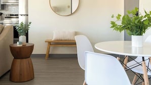 A modern living space with a kitchen, dining area, and a round mirror on the wall. - Unbeatable Location | Chic 1BR Apt | Walk to Beach (San Diego)