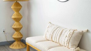 Een kamer met een bank, een ronde spiegel en een vloerlamp.