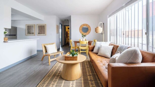 Een moderne woonkamer met een bank, stoelen, een salontafel en een eethoek.