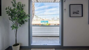 Una habitación con un ventanal grande, una planta en maceta y un cuadro en la pared.