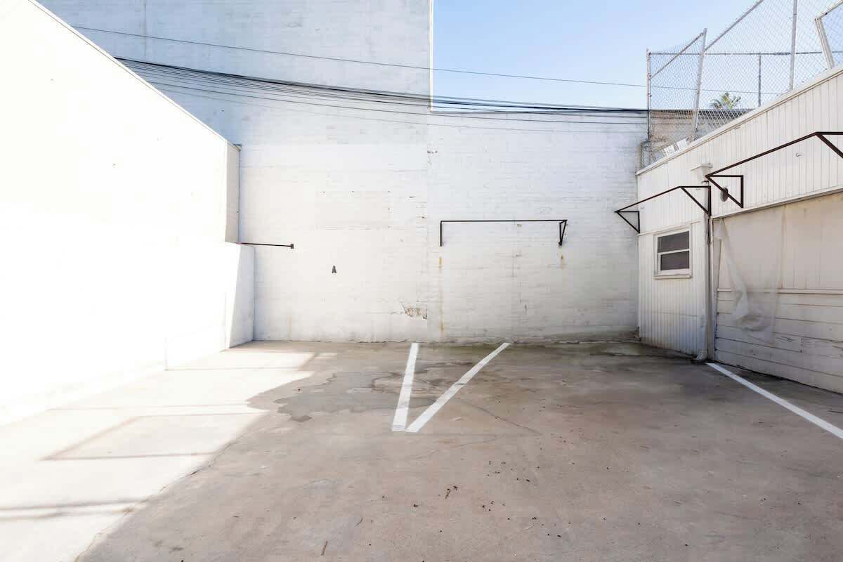 A vacant indoor space with concrete flooring, white walls, and a metal fence.
