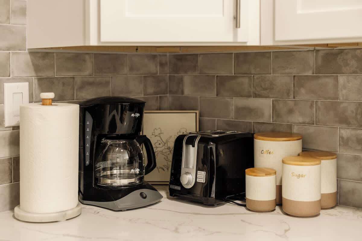 A kitchen with a coffee maker, toaster, and storage jars labeled 'Coffee' and 'Sugar'.
