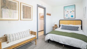 Een kamer met een bed, een bankje en kunstwerken in lijsten aan de muren.